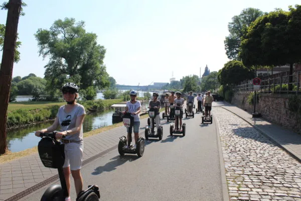 Menschen auf ihrem Segway fahren einen Uferweg entlang