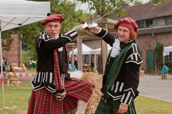 Zwei Schauspieler bei den Highland Games kreuzen ihre Klingen