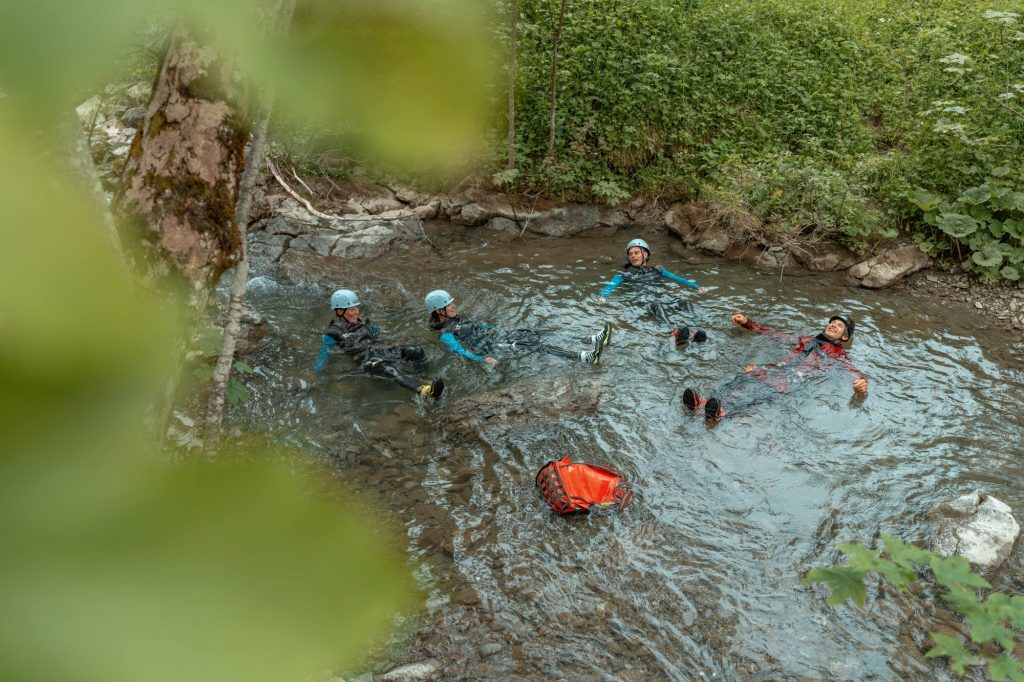 Blick auf Teilnehmer beim Canyoning von oben in einem Gewässer
