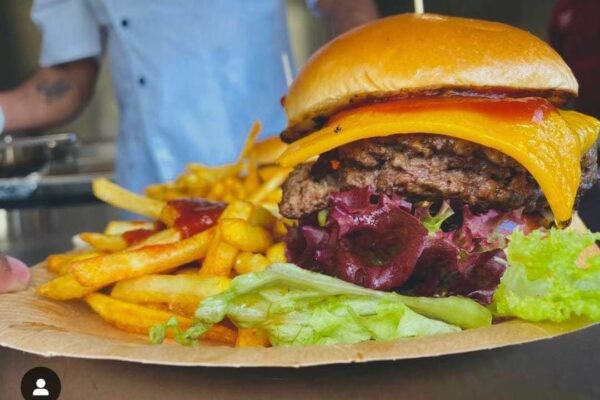 Man erkennt einen Burger Belegt mit Fleisch, Käse und Salat.