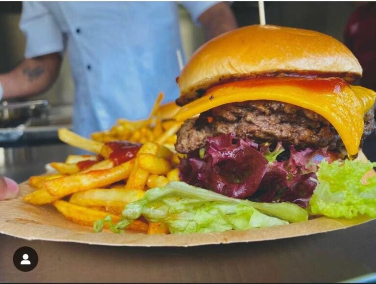 Man erkennt einen Burger Belegt mit Fleisch, Käse und Salat.