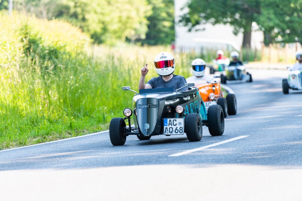Eine Person mit Helm in einem blau-schwarzen Hotrod bei der Dreiländer-Rallye in Aachen