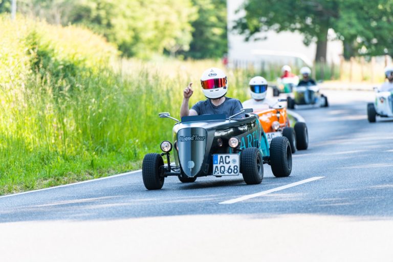 Eine Person mit Helm in einem blau-schwarzen Hotrod bei der Dreiländer-Rallye in Aachen
