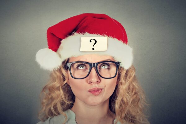 Eine blonde Frau mit Brille und Weihnachtsmütze schaut fragend nach oben bei dem Event Weihnachtliches Team-Quiz